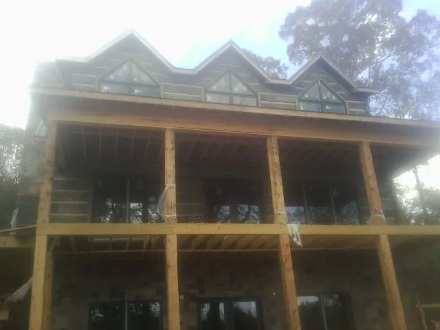 Dormers and porch framing on a large log home under construction — Roof Coating work by our crew in Martinsburg